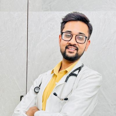 Portrait of Dr. Nikhil Gandhi, a top gastrologist in Bikaner, in his medical office, wearing a white coat and stethoscope, smiling confidently.