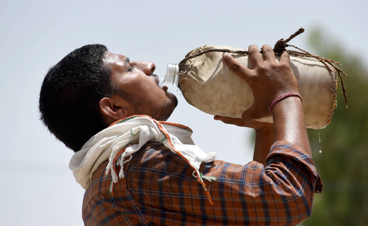 Man drinking water from a traditional bottle in Rajasthan to stay hydrated during the hot summer